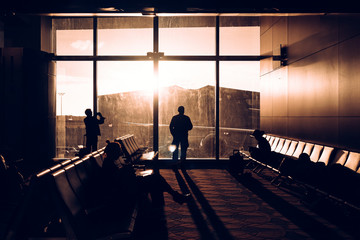 Silhouettes of People Sitting On Chair and standing near the window at the Airport
