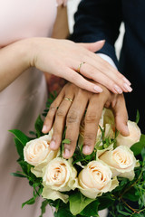The joined hands of the bride and groom at a wedding. Wedding rings on the fingers of the newlyweds. Hands close up. 
