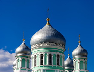 Fototapeta na wymiar Dome of the Orthodox Church against the blue sky with clouds in summer closeup