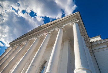 White columns of the Orthodox Church against the blue sky and white clouds in summer