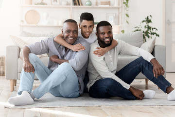 Portrait of happy preteen afro boy hugging father and grandpa at home