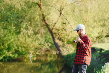 young fisherman fishes near the river. The concept of outdoor activities and fishing