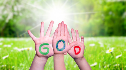 Children Hands Building Colorful Word God. Green Grass Meadow As Background