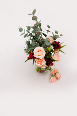 green eucalyptus and tender roses in a glass on a gray background