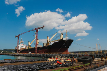 Fototapeta premium Big ship moored on huge floating dock with cranes for repair in shipyard.