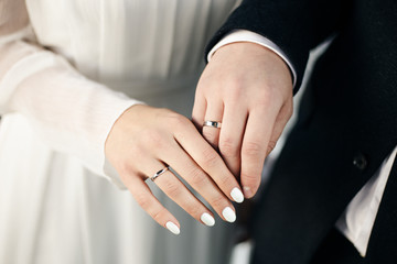 Obraz premium Połączone ręce młodej pary na weselu. Obrączki na palcach nowożeńców. Ręce z bliska.