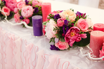 wedding table decoration bouquets of flowers, candles and dyed branches
