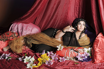 eastern woman in black clothes lies on pillows