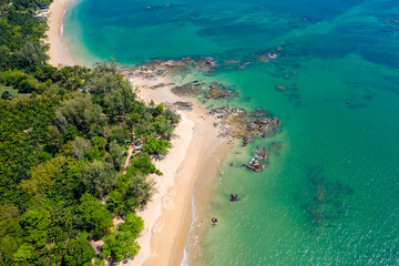 Fototapeta na wymiar Aerial view of a beautiful, empty tropical beach surrounded by lush green foliage