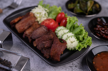 Fried pork topped with sesame placed in a black dish.