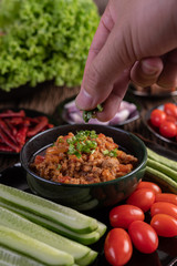 Sweet pork in a black bowl, complete with cucumbers, long beans, tomatoes, and side dishes