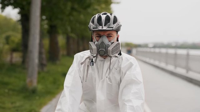 close-up of a young man in a protective suit, mask and helmet rides a bicycle