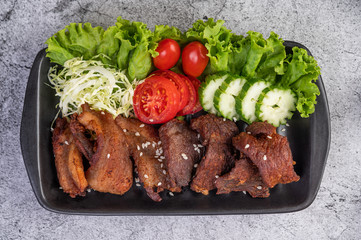 Fried pork topped with sesame placed in a black dish.