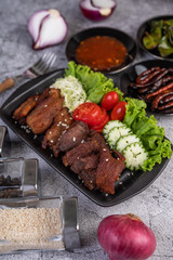 Fried pork topped with sesame placed in a black dish.