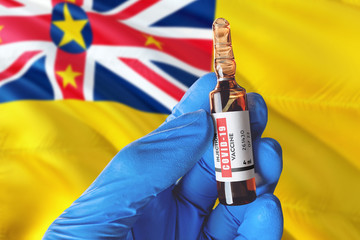 Niue flag with Coronavirus Covid-19 concept. Doctor with blue protection medical gloves holds a vaccine bottle. coronavirus covid 19 vaccine research.