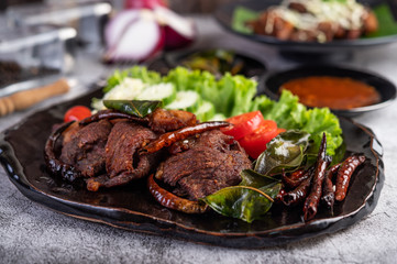 Fried pork topped with sesame placed in a black dish.