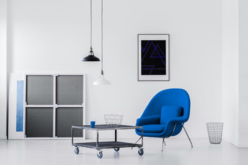 Blue armchair and coffee table in a modern room interior. Real photo