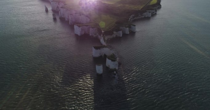 Slow panning up movement reveals Old Harry Rocks and surrounding coastline in sunshine