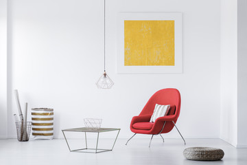 Real photo of a modern living room interior with a red armchair and yellow painting