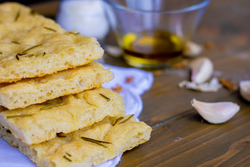Homemade Italian Focaccia Modenese, with rosemary and olive oil on a rustic wooden background.