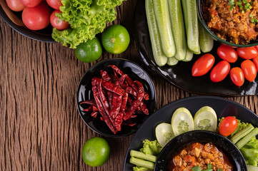 Sweet pork in a black bowl, complete with cucumbers, long beans, tomatoes, and side dishes