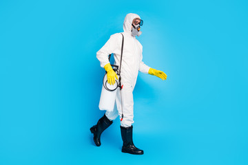 Full length profile side photo of medical worker man go walk clean home house ncov infection stop spread epidemic wear latex hazmat boots gas mask gloves isolated blue color background