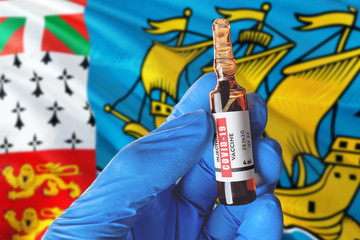 Saint Pierre And Miquelon flag with Coronavirus Covid-19 concept. Doctor with blue protection medical gloves holds a vaccine bottle. coronavirus covid 19 vaccine research.