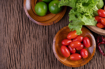 Palm sugar, red onions, dried peppers, tomatoes, cucumbers, yard long beans and lettuce in a bowl.