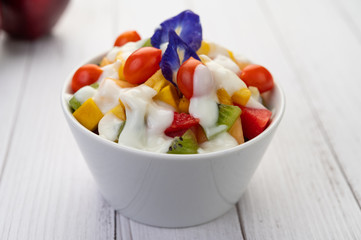 Fruit salad in a bowl on the wooden floor.