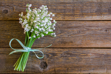 Beautiful bouquet of white lily of the valley flowers on a wooden table