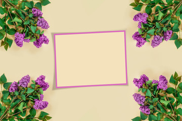Purple lilac branches on  beige paper background. Greeting card with place for your text.