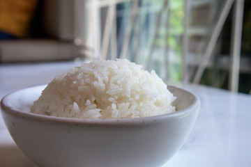 Organic Thai Jasmine rice grain in a cup is preparing for cooked. Selective focus.