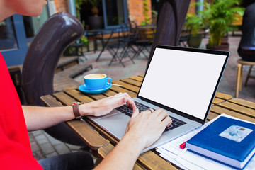 Man freelancer skilled distance worker keyboarding on laptop computer with empty mock up copy space screen background for promotional content while sitting in coffee shop outdoors