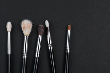 brushes for make-up of different sizes lie on a black background. copyspace.