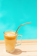 Greek coffee drink called frappe coffee at the edge of a swimming pool (selected focus)