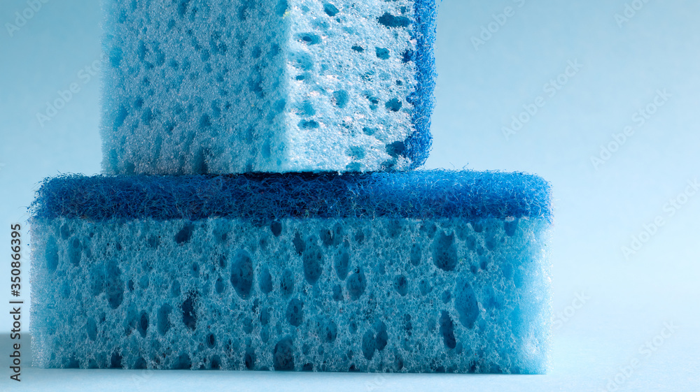 Wall mural Two blue sponges used for washing and erasing dirt used by housewives in everyday life. They are made of porous material such as foam. Detergent retention, which allows you to spend it economically