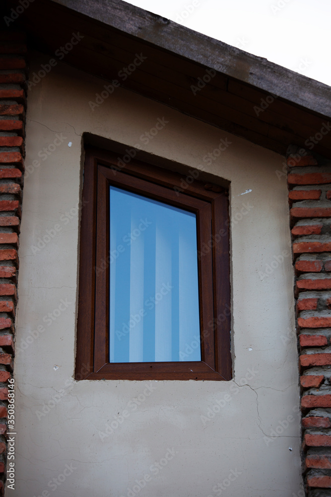 Wall mural wooden brown window on a white plastered wall from the outside