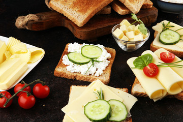 rolled slices of golden gouda cheese or cream cheese on a sandwich garnished with sliced cucumber and herbs. bread or toast with cheese for breakfast