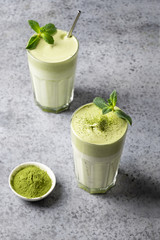 Two glasses of Dalgona Matcha latte tea. Close up. Vertical format.