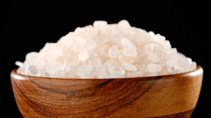 pink Himalayan salt in wooden bowl. black background macro