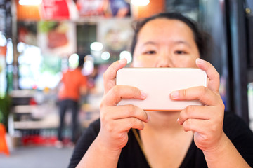 Asian woman playing game on mobile phone during waiting for food in the restaurant