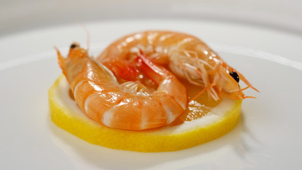 shrimps on a slice of lemon in white plate closeup. top view