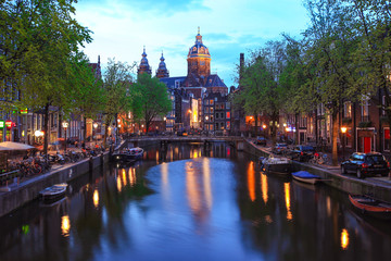 Fototapeta na wymiar Church of St Nicholas over old town canal illuminated at night Amsterdam, Holland