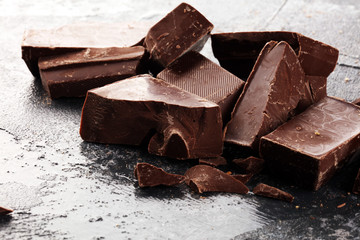 close up of bitter chocolate bars and broken piesces on rustic background.