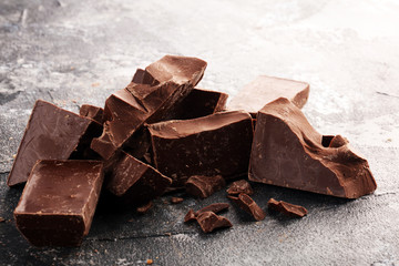 close up of bitter chocolate bars and broken piesces on rustic background.