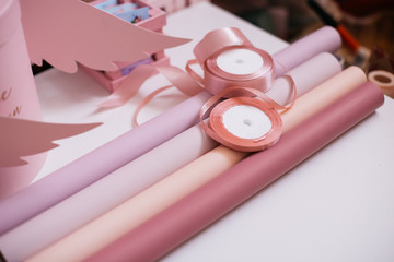 wrapping paper of bright pink, pale pink, salmon and purple with ribbons on a white table. preparation for packaging and decorating a bouquet of flowers for the holiday.