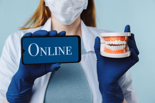 Portrait Of Beautiful Female Dentist Posing In Dental Clinic Holding Smartphone With Green Screen And Presenting Mobile App Or Website To Camera, Copy Space.