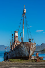 Old rusting whaler moored beneath blue sky