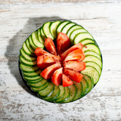 chopped cucumbers and tomatoes in a black plate on a light wood background