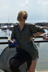 middle-aged blonde woman on a pier against the background of boats